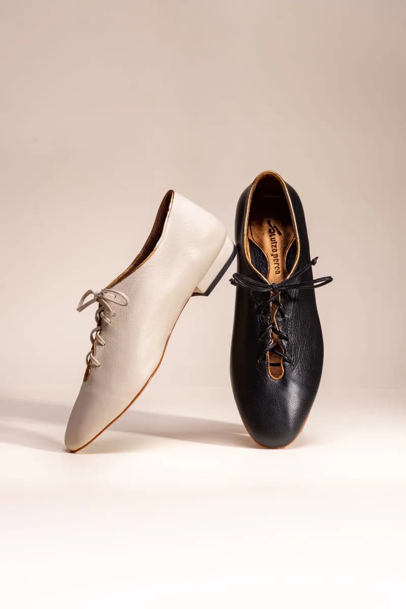 Par de sapatos jazz de couro, um branco e um preto, de pé em fundo claro